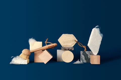 Sqwishful zero waste kitchen and home accessories: plant-powered and plastic-free pop up sponge, scrub sponge, and dish brush with wood and marble blocks and bubbles.