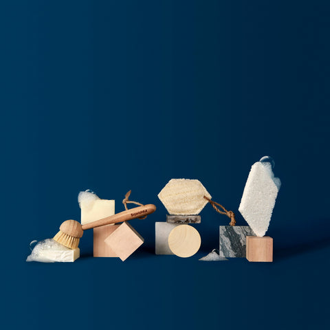 Sqwishful zero waste kitchen and home accessories: plant-powered and plastic-free pop up sponge, scrub sponge, and dish brush with wood and marble blocks and bubbles.
